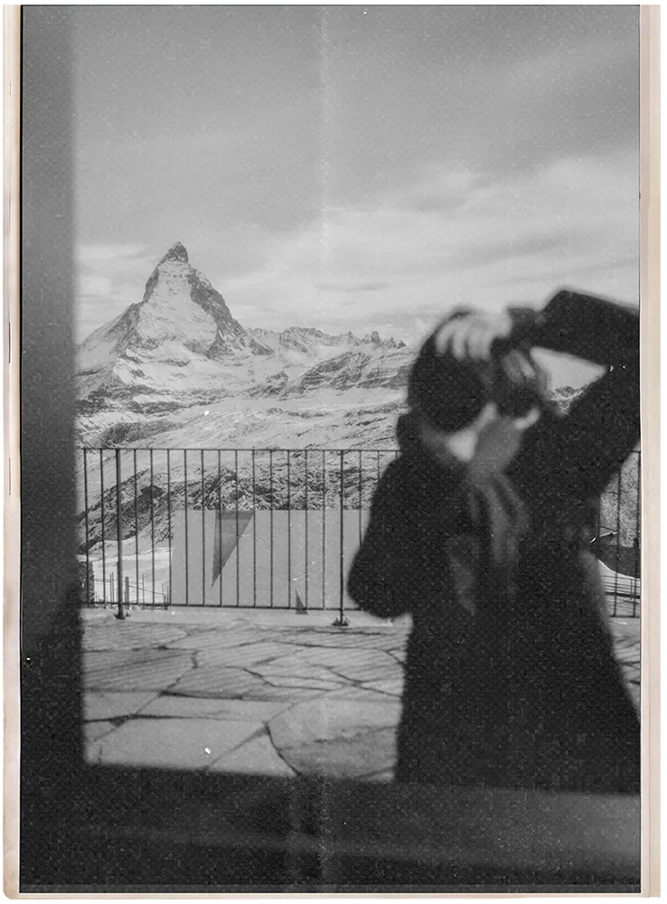 Nina Volpini, brazilian photographer in Madrid, editorial portrait with a camera and mountains in the background